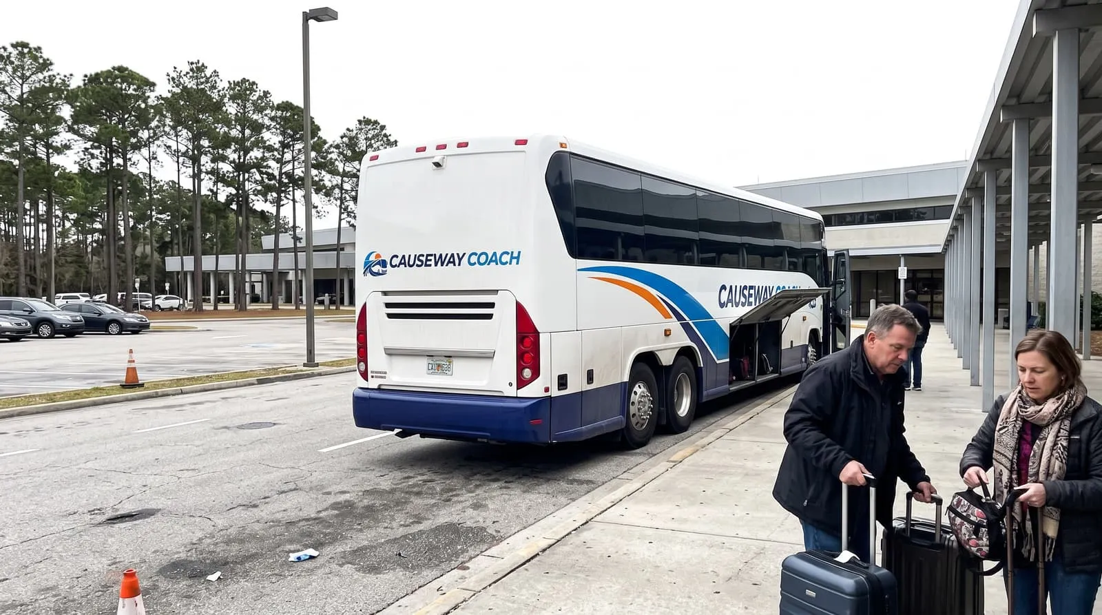 Travellers with suitcases at the open luggage bay of a Causeway Coach motorcoach outside Jacksonville International Airport