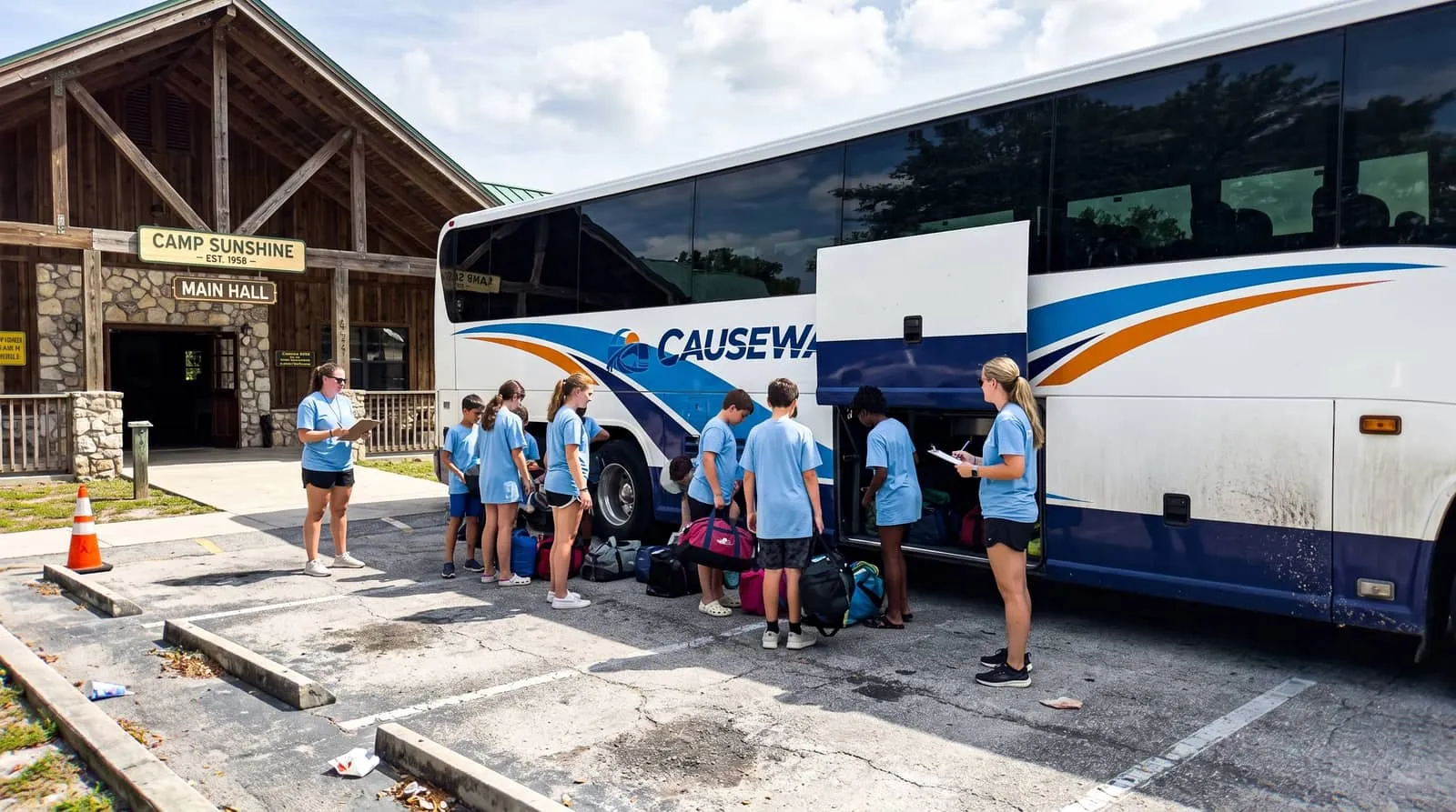 Youth group boarding a Causeway Coach bus with adult leaders counting heads